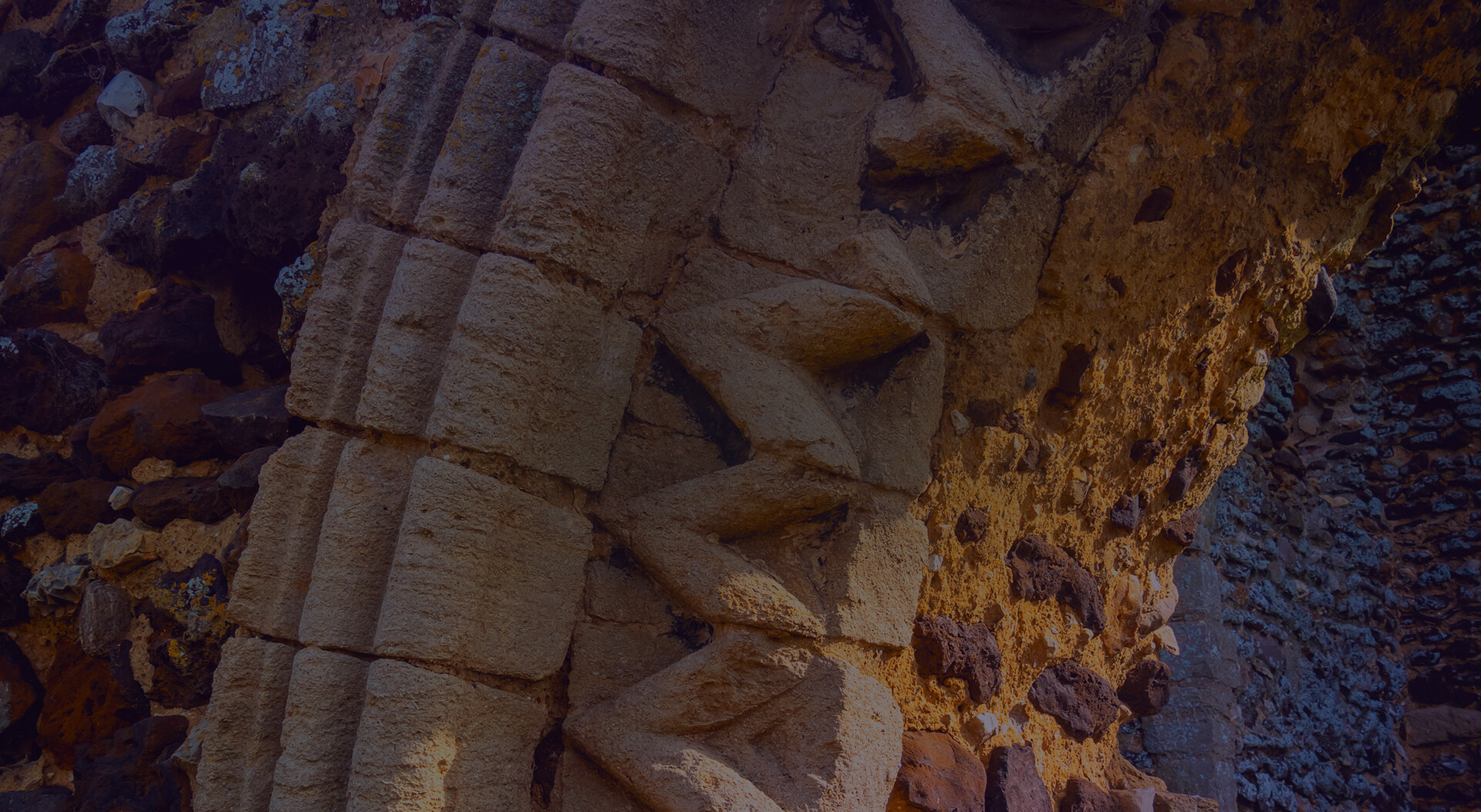 Close-up of an ancient stone structure with weathered, interlocking blocks, revealing the passage of time on its rugged surface.