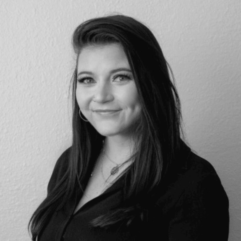 A black and white portrait of a smiling woman with long hair, looking confidently to the side.
